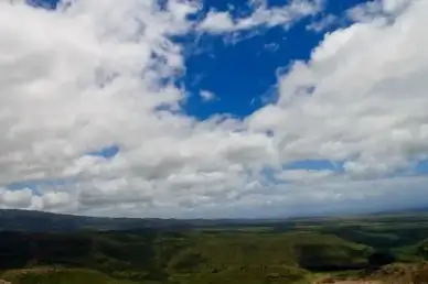 puffy clouds over green hills