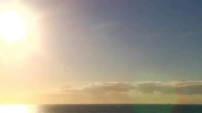 sun and cloud movement above calm sea
