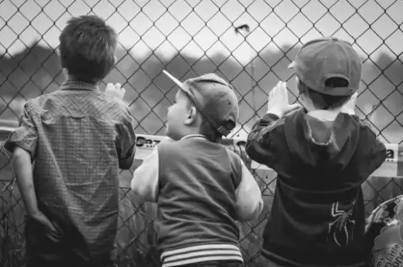 three boys are watching baseball