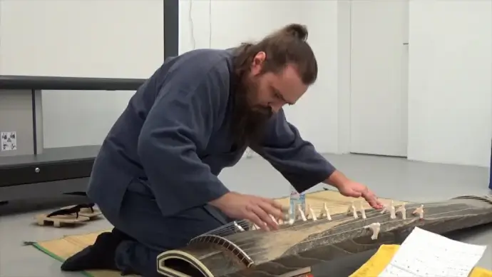 western man performing asian traditional musical instrument