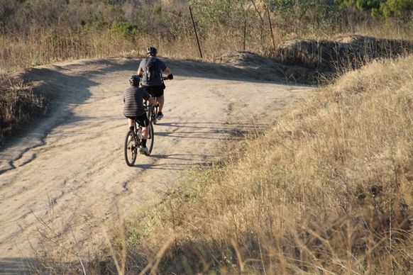 2 bicyclists riding on dirt trail