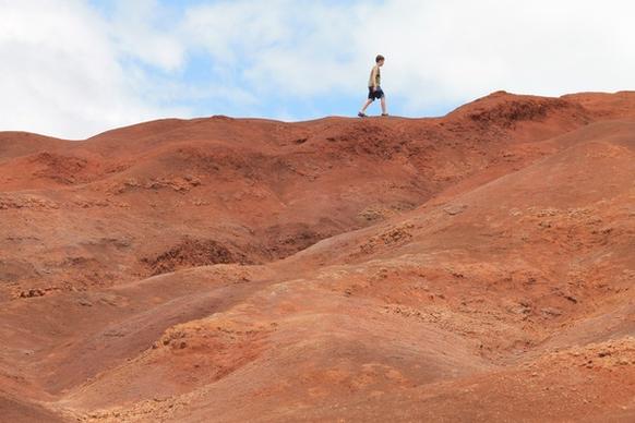 boy walking on red dirt hills