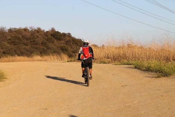 cyclist riding bicycle on dirt path