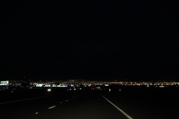 dark street leading to city lights at night