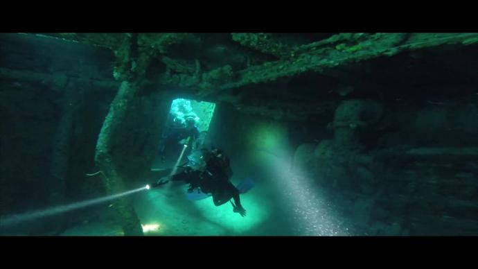 divers discovering wrecked ship in deep sea