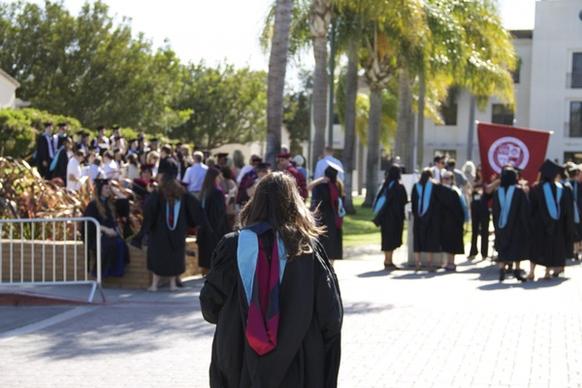 girl in graduation robe walking to crowd