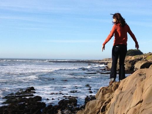 girl standing on rocks on ocean coast