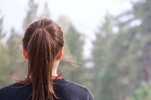 girl with ponytail looking at forest