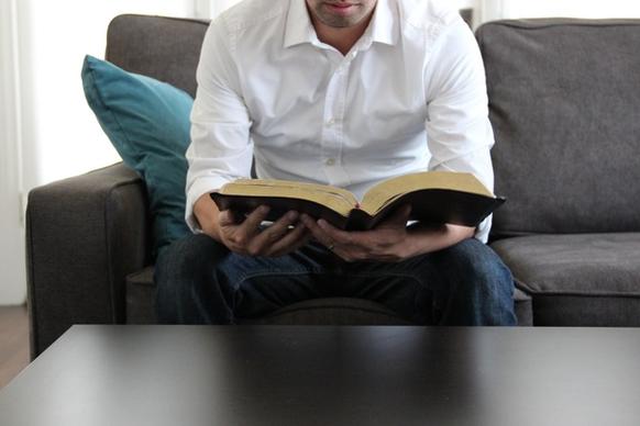 man on couch reading bible