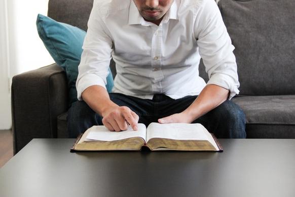 man on couch reading bible
