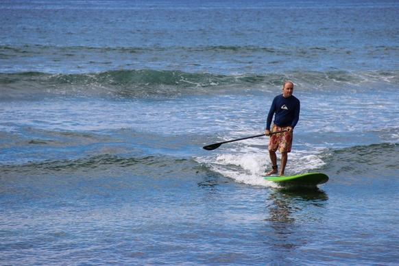 man riding paddle board in ocean