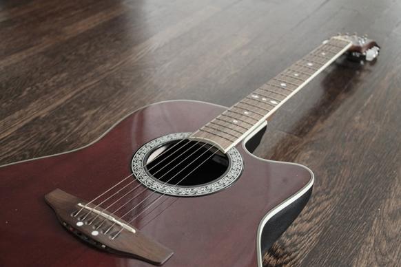 red acoustic guitar angled on wood floor