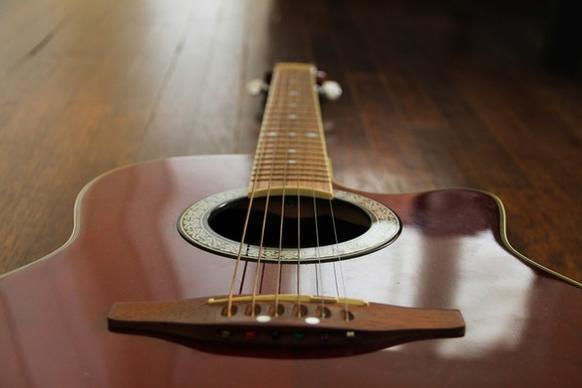 red acoustic guitar on wood floor
