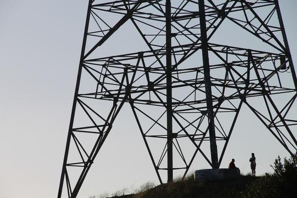 silhouette of people under electric tower