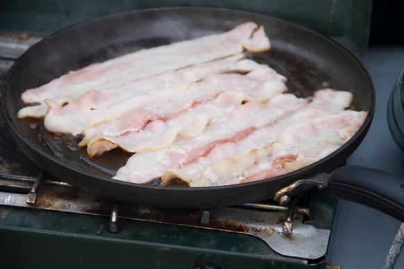 strips of bacon cooking on a skillet