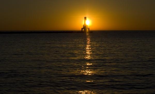 sun behind the lighthouse at port washington wisconsin