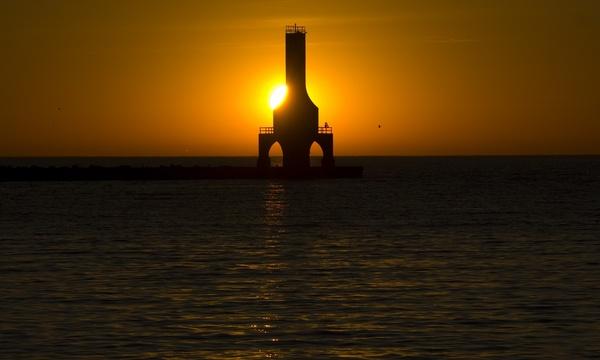 sun behind the lighthouse at port washington wisconsin
