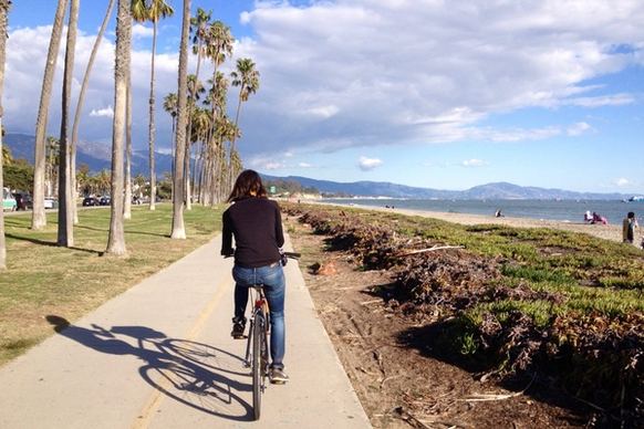 woman riding bicycle on path along beach