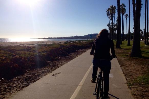 woman riding bicycle on path by beach