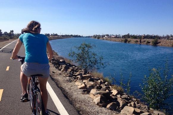 woman riding bike on path along river