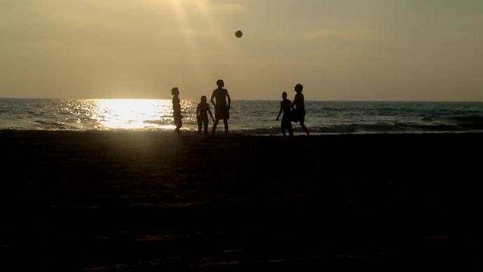 youth excited with football on beach at dusk